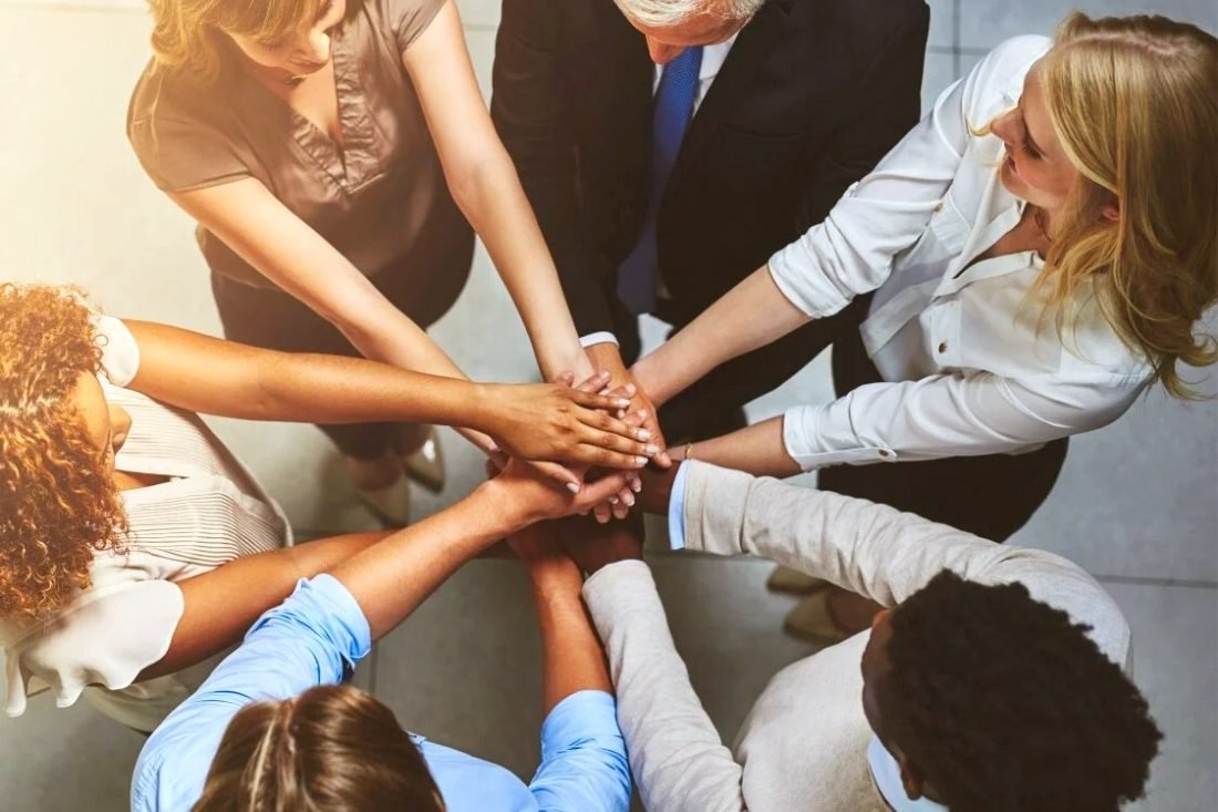 Hands joined together in the middle of a group